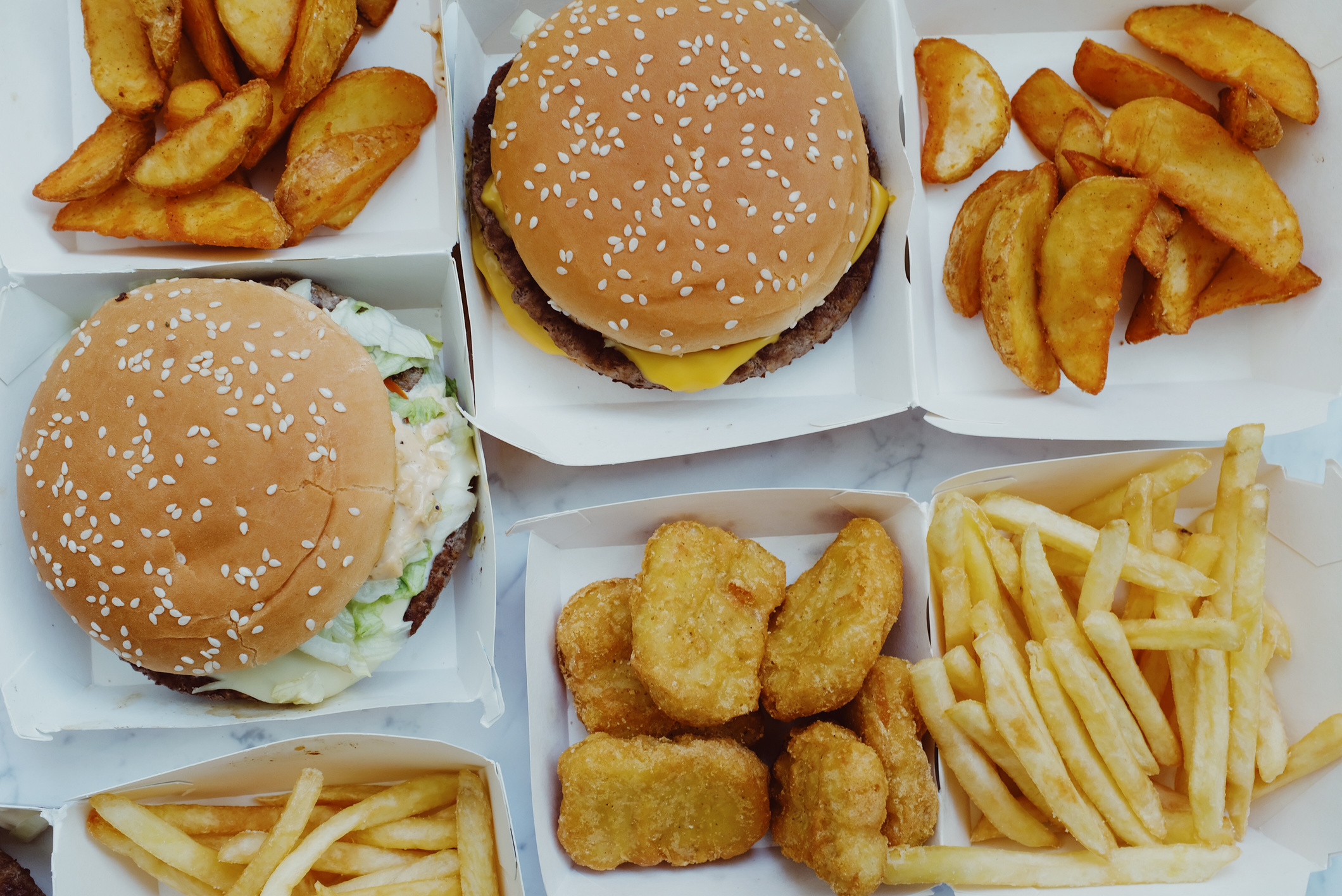 Appetizing fast food placed in boxes on marble background
